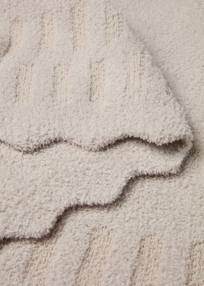 Cream blanket with scalloped edges laying folded