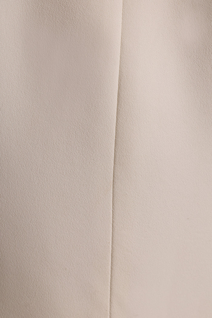 Close-up of the cream crepe fabric and center seam on a white tapered blazer.