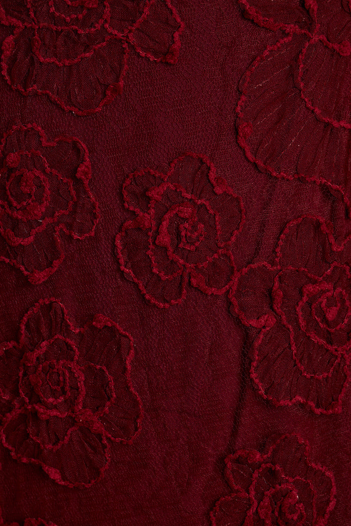 Close-up of burgundy rose floral lace appliqué fabric.