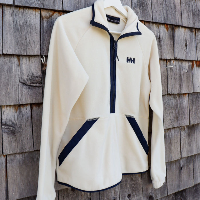 White fleece jacket with navy accents on a wooden wall