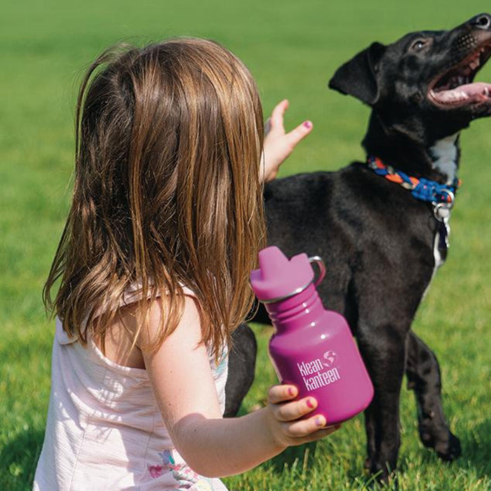 Lifestyle shot of a small girl holding a stainless steel water bottle with a sippy cap