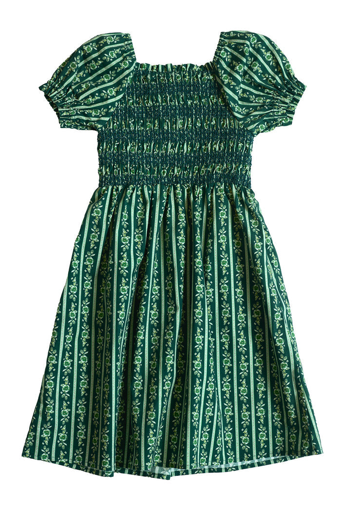The Mini Sunday Best Dress in Pine Felicity Floral by Ivy City Co is a green cotton dress for girls, featuring puffed short sleeves, a gathered smocked bodice, and vertical stripes adorned with the Pine Felicity Floral pattern in lighter green tones. This knee-length dress showcases a charming, vintage-inspired style.