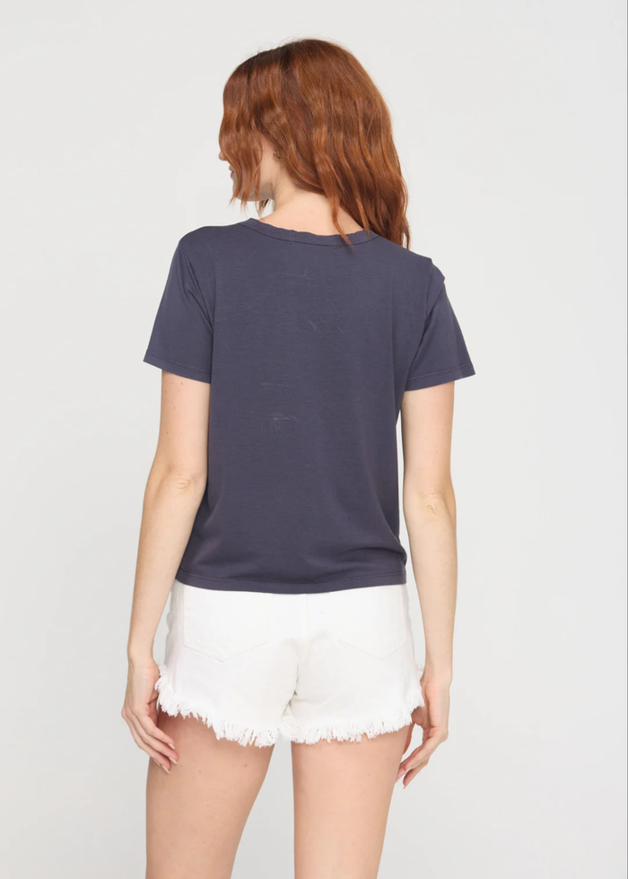 Woman turned around wearing a charcoal grey crewneck t-shirt with white denim shorts