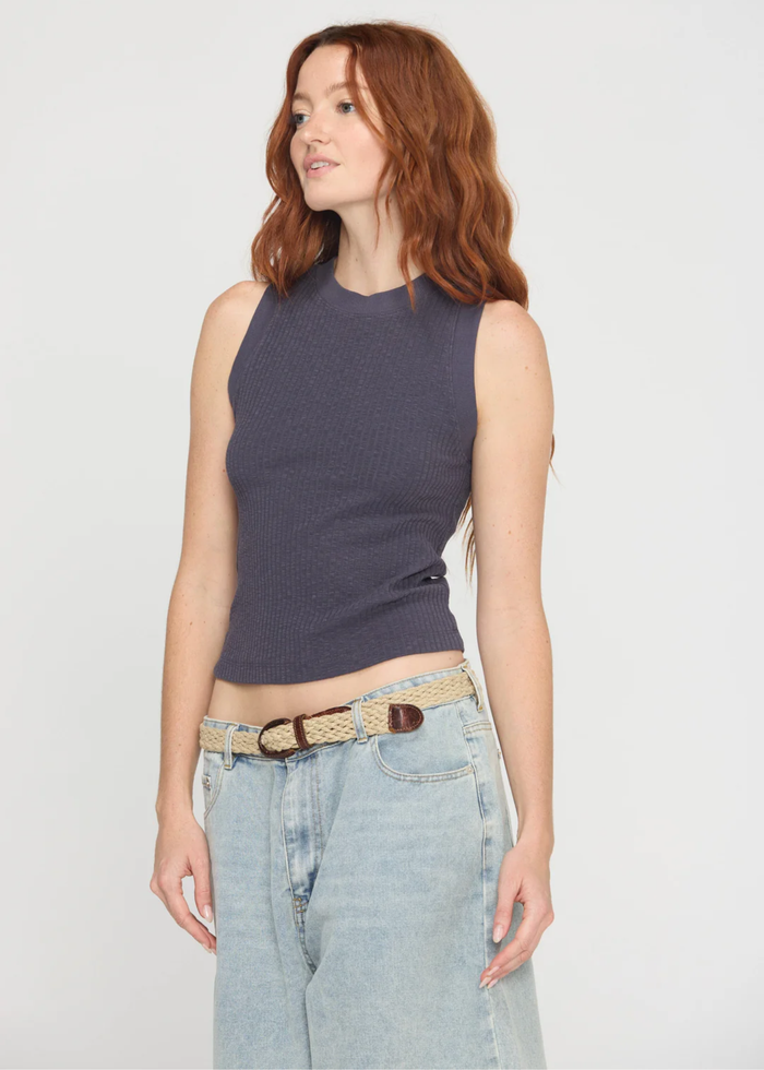 Woman wearing a charcoal grey tank top with a crew neck and a racerback along with denim bottoms and a belt