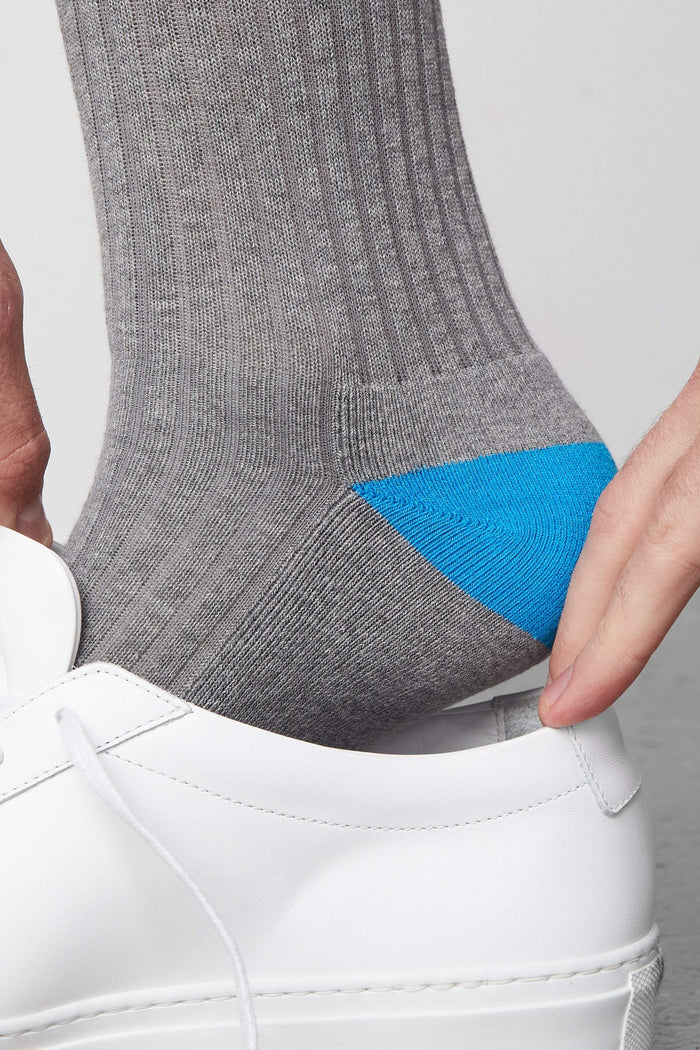 Side view of a man putting on a shoe and wearing Everyday Extended Crew Sock in Grey Heather