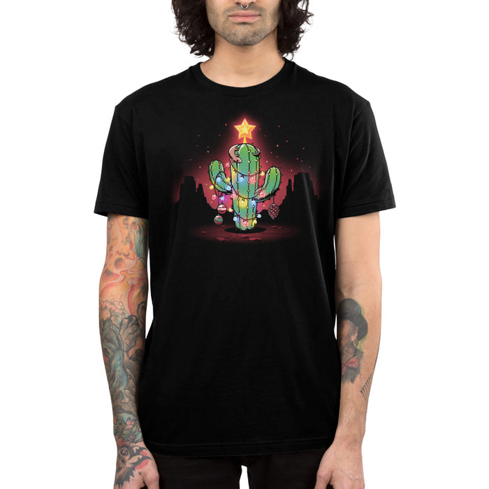 Premium Cotton T-shirt_TeeTurtle A Desert Christmas Black apparel featuring an artistic cactus with lights, ornaments, a star, and a gecko on top in front of a grand canyon inspired silhouetted background.