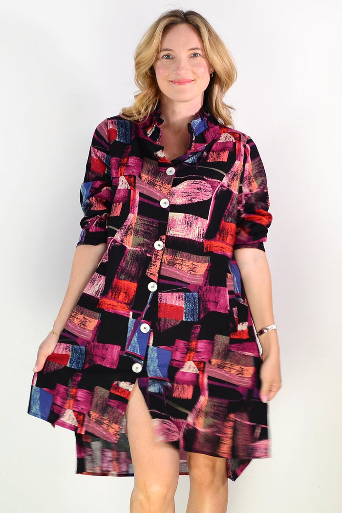 Abstract pink Wishstone tunic shirt with flowing fabric and relaxed fit, showcased on a hanger.