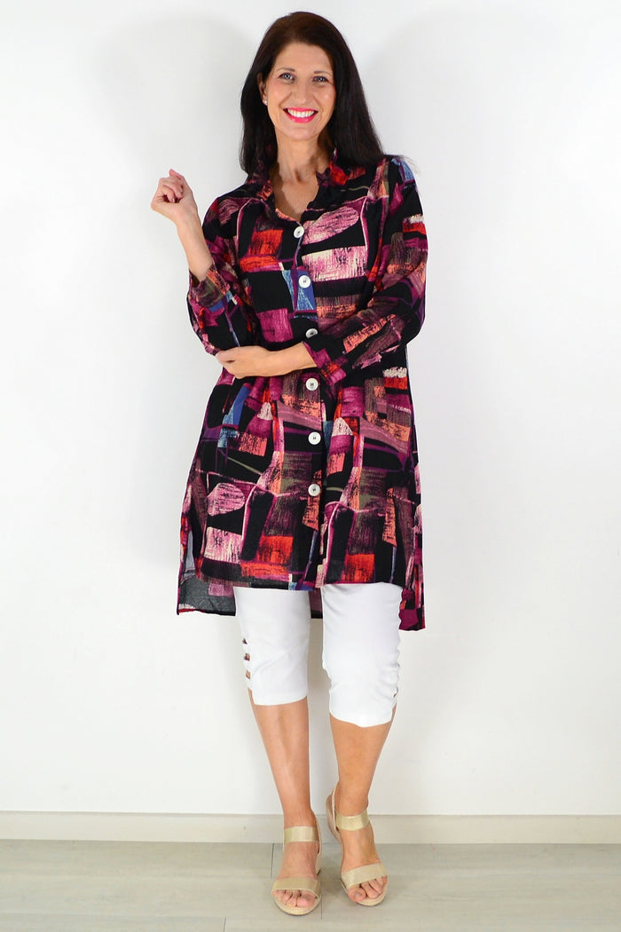 Abstract pink wishstone tunic shirt with loose fit and long sleeves, displayed on a hanger against a neutral background.