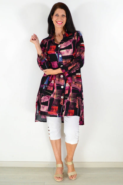 Abstract pink wishstone tunic shirt with loose fit and long sleeves, displayed on a hanger against a neutral background.