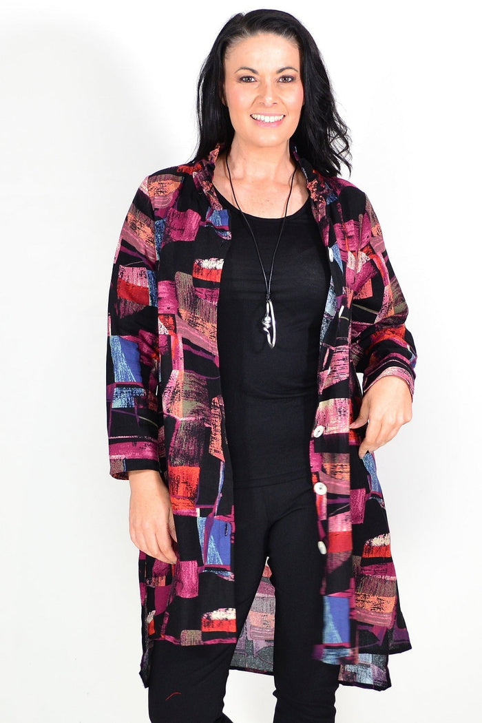 Abstract pink wishstone tunic shirt with flowing fabric and long sleeves, displayed on a hanger.