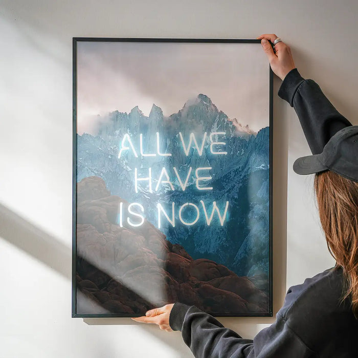 Framed mountain landscape art print featuring the glowing neon slogan All We Have Is Now on high-quality archival paper.