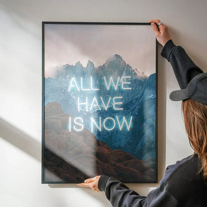 Framed mountain landscape art print featuring the glowing neon slogan All We Have Is Now on high-quality archival paper.