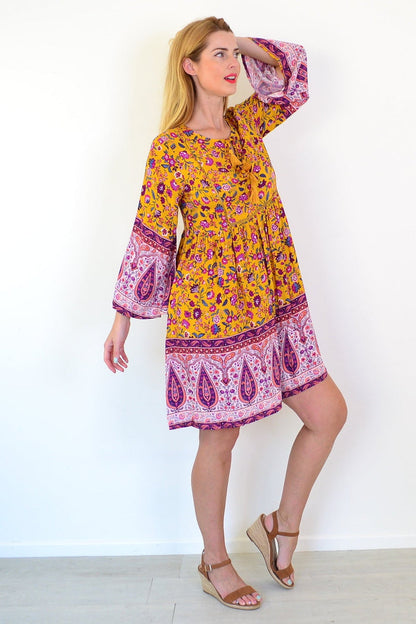 Dream Amelia Mustard Bohemian Tunic Dress displayed on a hanger with flowing fabric and intricate boho patterns.