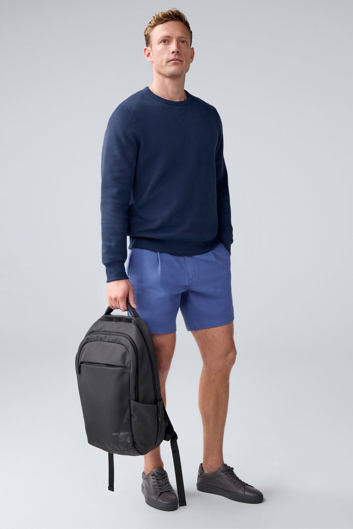 Full body image of man holding Atlas Everyday Backpack by his side