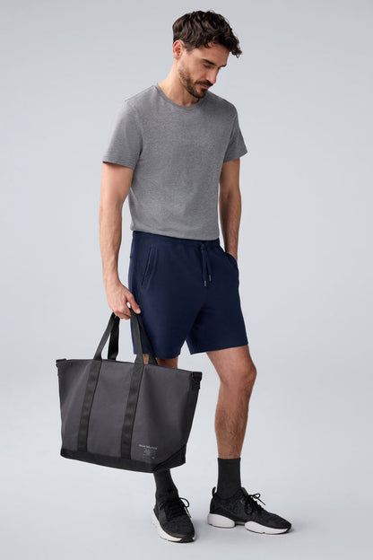 Full body image of man holding Atlas Tote by his side