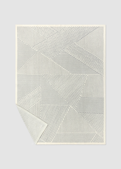 Grey and white striped blanket on a grey background with a corner folded