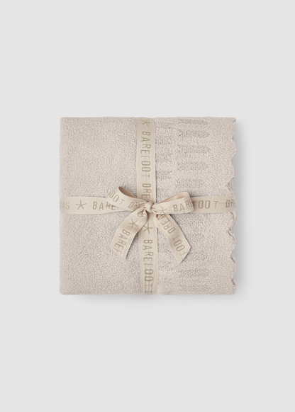 Cream blanket folded and tied with a cream ribbon sitting on a grey background