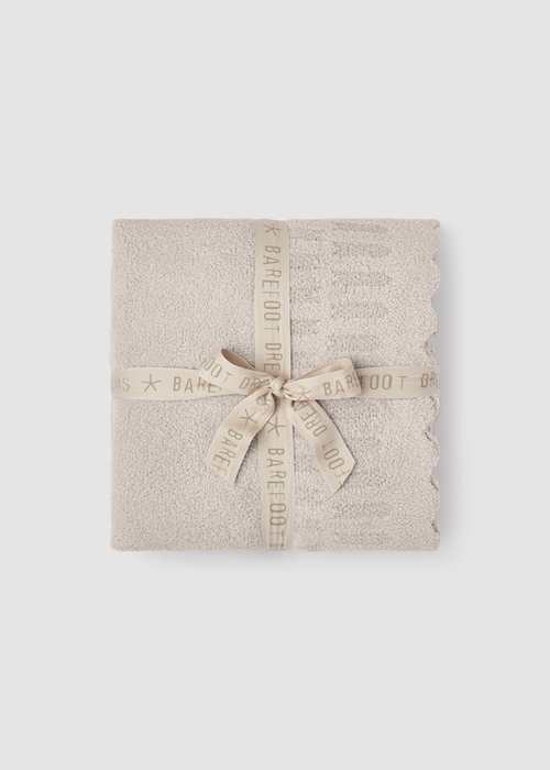 Cream blanket folded and tied with a cream ribbon sitting on a grey background