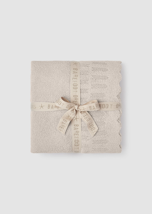 Cream blanket folded and tied with a cream ribbon sitting on a grey background