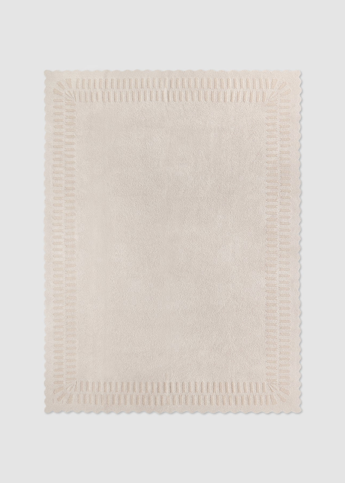 Cream blanket laying on a grey background
