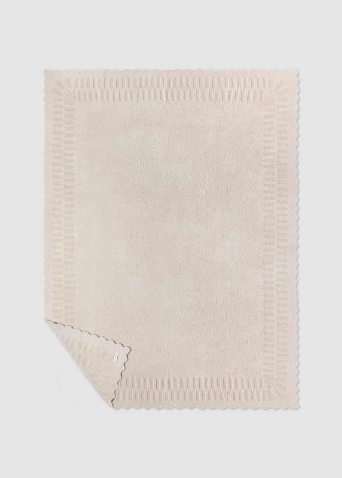 Cream blanket laying on a grey background