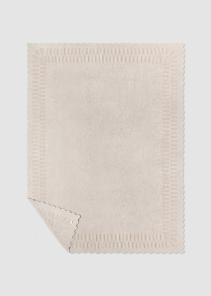 Cream blanket laying on a grey background