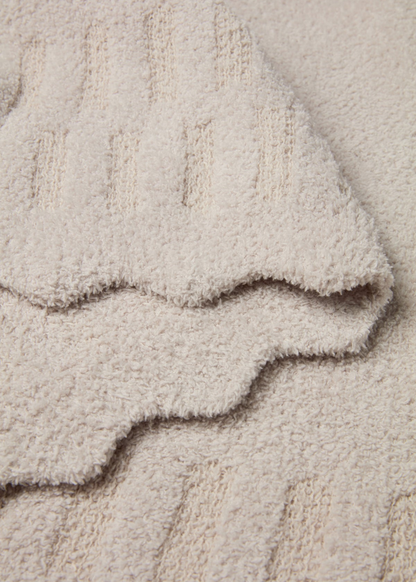 Cream blanket with scalloped edges laying folded