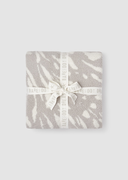 Grey and cream animal pattern blanket folded on a grey background with a white bow