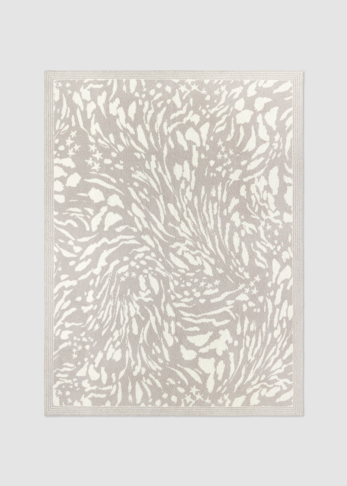 Grey and cream animal print blanket laying on a grey background
