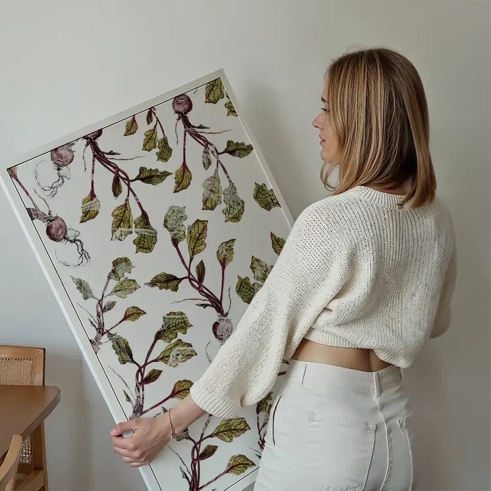 Woman holding a large, unframed botanical beetroot print on thick archival art paper, featuring green leaves and purple beets.