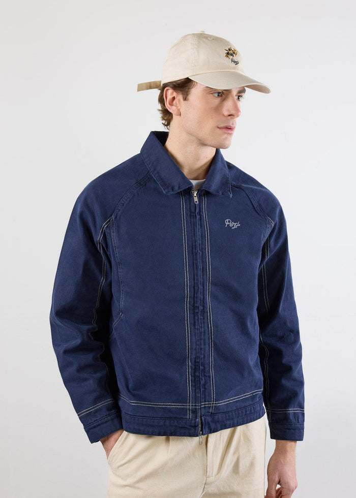 A model wears the Percival Calabria Harrington Jacket in navy cotton, featuring a zip-up front and contrast stitch details.