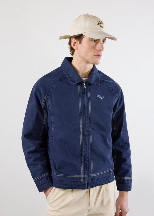 A model wears the Percival Calabria Harrington Jacket in navy cotton, featuring a zip-up front and contrast stitch details.