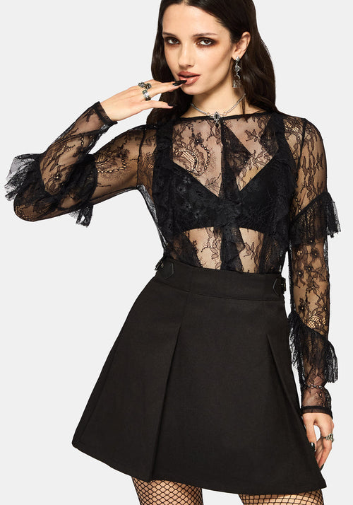 Woman wearing a black lace top and black mini skirt on a white studio background.