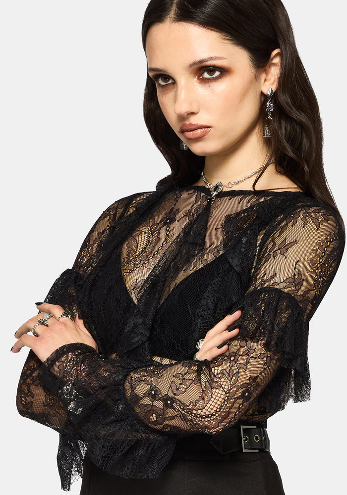 Woman wearing a black lace long sleeve top against a white background