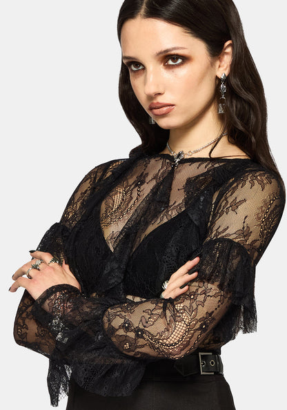 Woman wearing a black lace long sleeve top against a white background