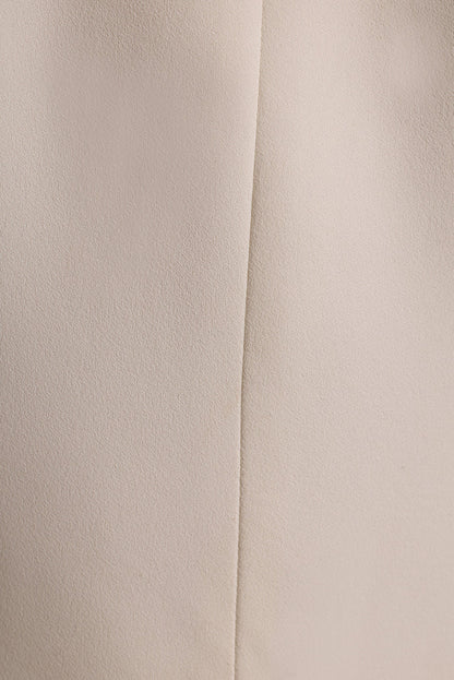 Close-up of the cream crepe fabric and center seam on a white tapered blazer.