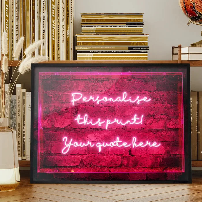 Custom neon-style print in a black frame featuring glowing pink handwritten text against a dark brick wall background.