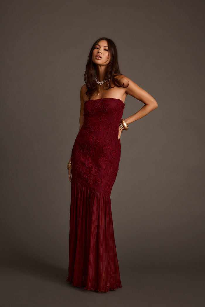 Front view of a strapless burgundy rose lace maxi dress with a pleated mermaid hem.