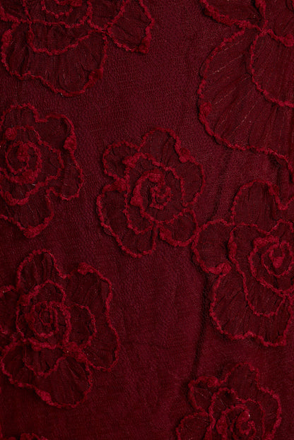 Close-up of burgundy rose floral lace appliqué fabric.