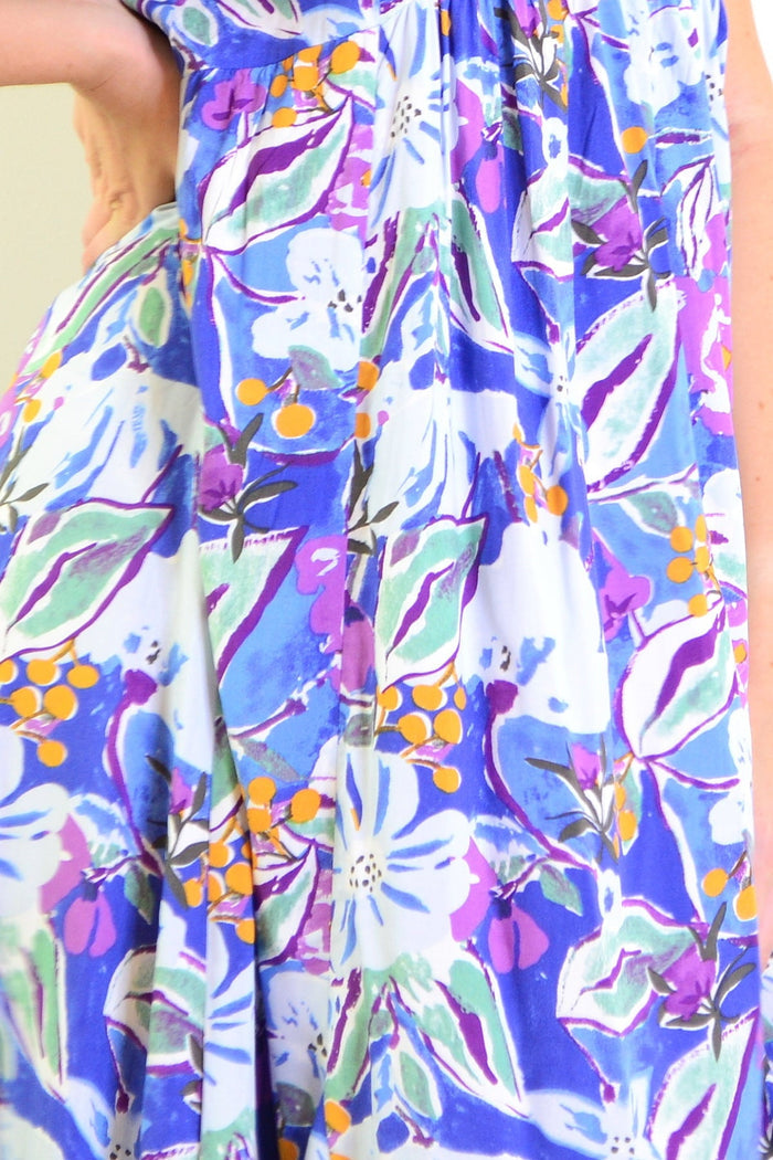 Hourglass summer garden tunic dress with floral pattern and lightweight fabric, displayed on a hanger.