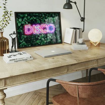 Framed neon DISCO sign print featuring vibrant pink and blue lettering set against a lush green botanical leaf background.