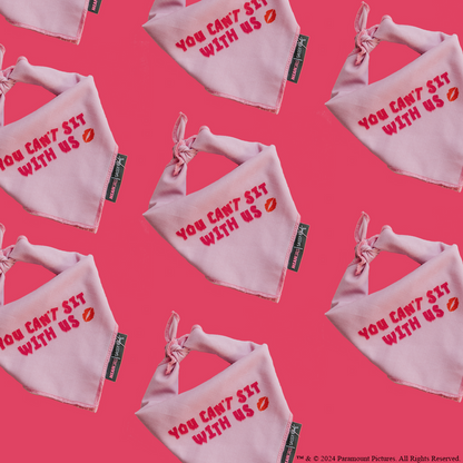 The Sassy Woof Dog Bandana - Mean Girls™ You Can't Sit With Us features a bold pink pattern with red text and lipstick kiss marks—perfect for stylish pups who want to stand out.