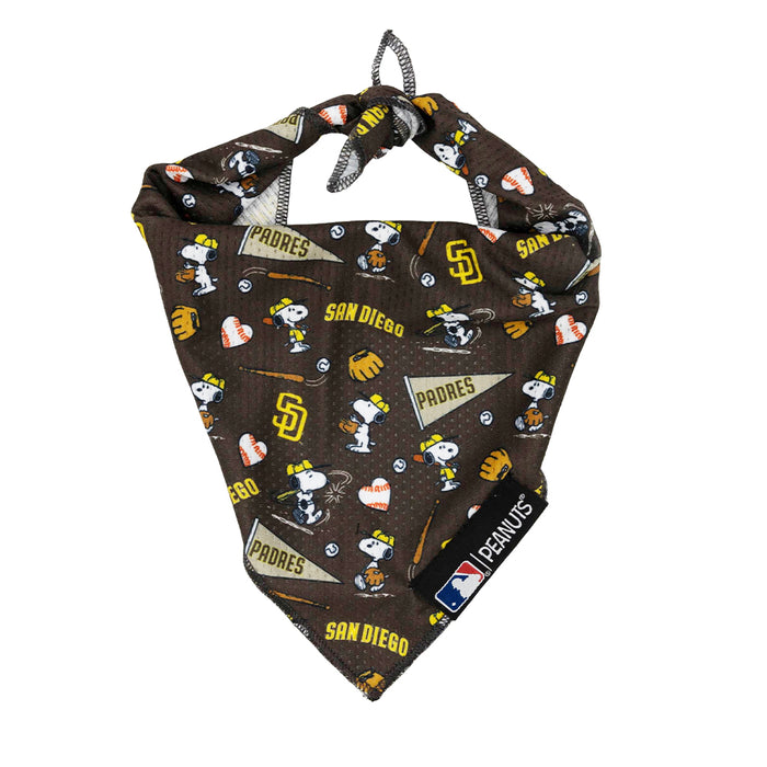 The Sassy Woof Dog Bandana - MLB™ x Peanuts™ San Diego Padres™ is brown and features Snoopy, Woodstock, baseballs, gloves, pennants, and San Diego Padres text. Peanuts™ and MLB™ tags are attached.