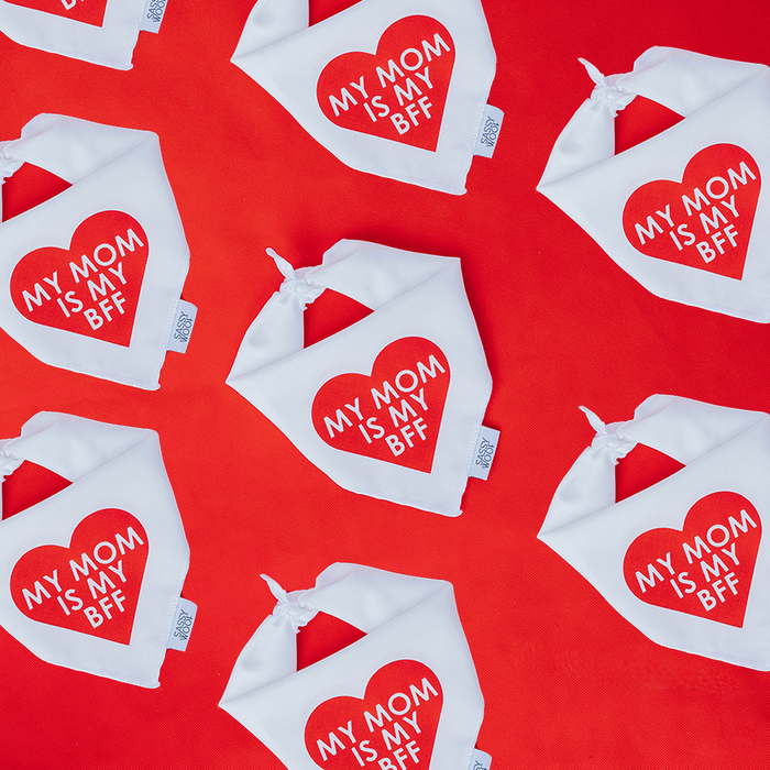 Sassy Woof's "Dog Bandana - My Mom is my BFF (RED)" features lightweight cotton bandanas with red heart designs, arranged on a vibrant red background.