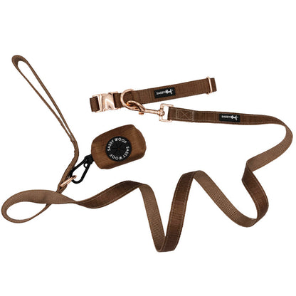 Sassy Woof’s Dog Collar Three Piece Bundle - Teddy features a brown collar and matching leash from the Teddy Collection, both adorned with rose gold-colored metal buckles. The bundle also includes a round black tag embossed with “Sassy Woof.” The slightly coiled leash comes with a comfortable loop handle.