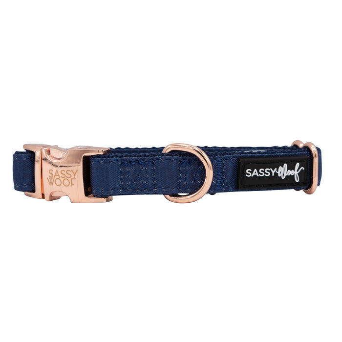 A navy blue Sassy Woof Dog Collar from the Twilight Three Piece Bundle, featuring rose gold hardware, a Sassy Woof–engraved buckle, a black tag with "Sassy Woof" in white script, and a sturdy metal D-ring for attaching a leash.