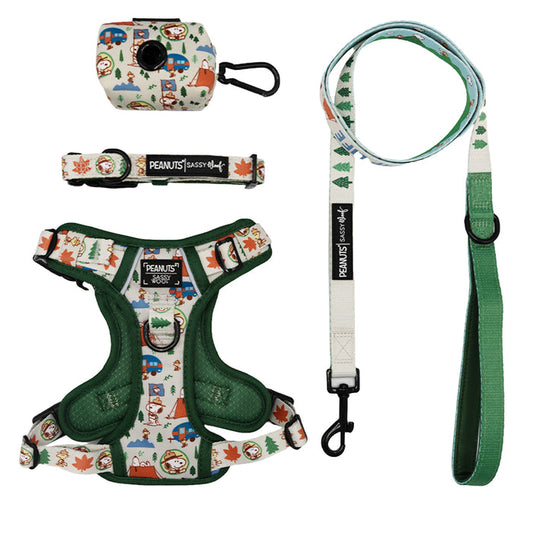 The Sassy Woof Dog Four Piece Bundle - Peanuts™ Beagle Scouts includes a Snoopy-themed harness, collar, leash, and waste bag holder with festive icons and green accents—perfect holiday pet accessories for Peanuts fans.