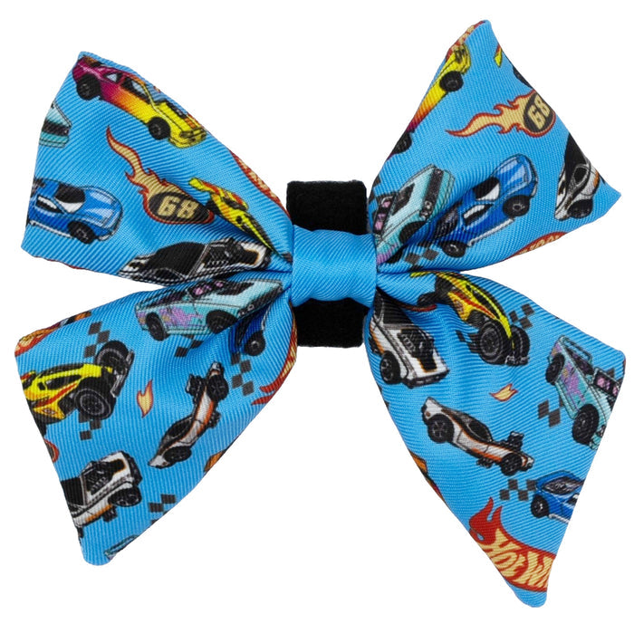 The Dog Sailor Bow - Hot Wheels™ by Sassy Woof features colorful cartoon cars, checkered flags, and flames on a bright blue background with a black center—perfect for stylish pups who love fun car designs.