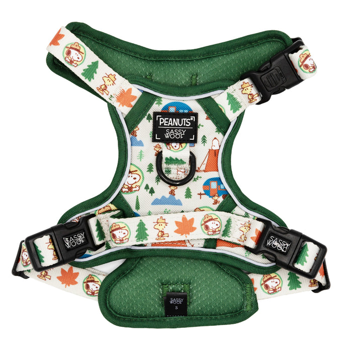 The Sassy Woof Dog Step-in Harness - Peanuts™ Beagle Scouts features a green and white design with Peanuts characters, trees, and leaves. This reflective harness has adjustable black buckles and PEANUTS x Sassy Woof branding on the front.