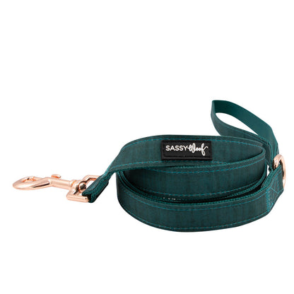 The Sassy Woof Dog Two Piece Bundle - Forest features a stylish teal leash with a rose gold clasp, matching handle, and logo patch. Pair with the adjustable harness for comfort. The items are coiled neatly against a white backdrop.